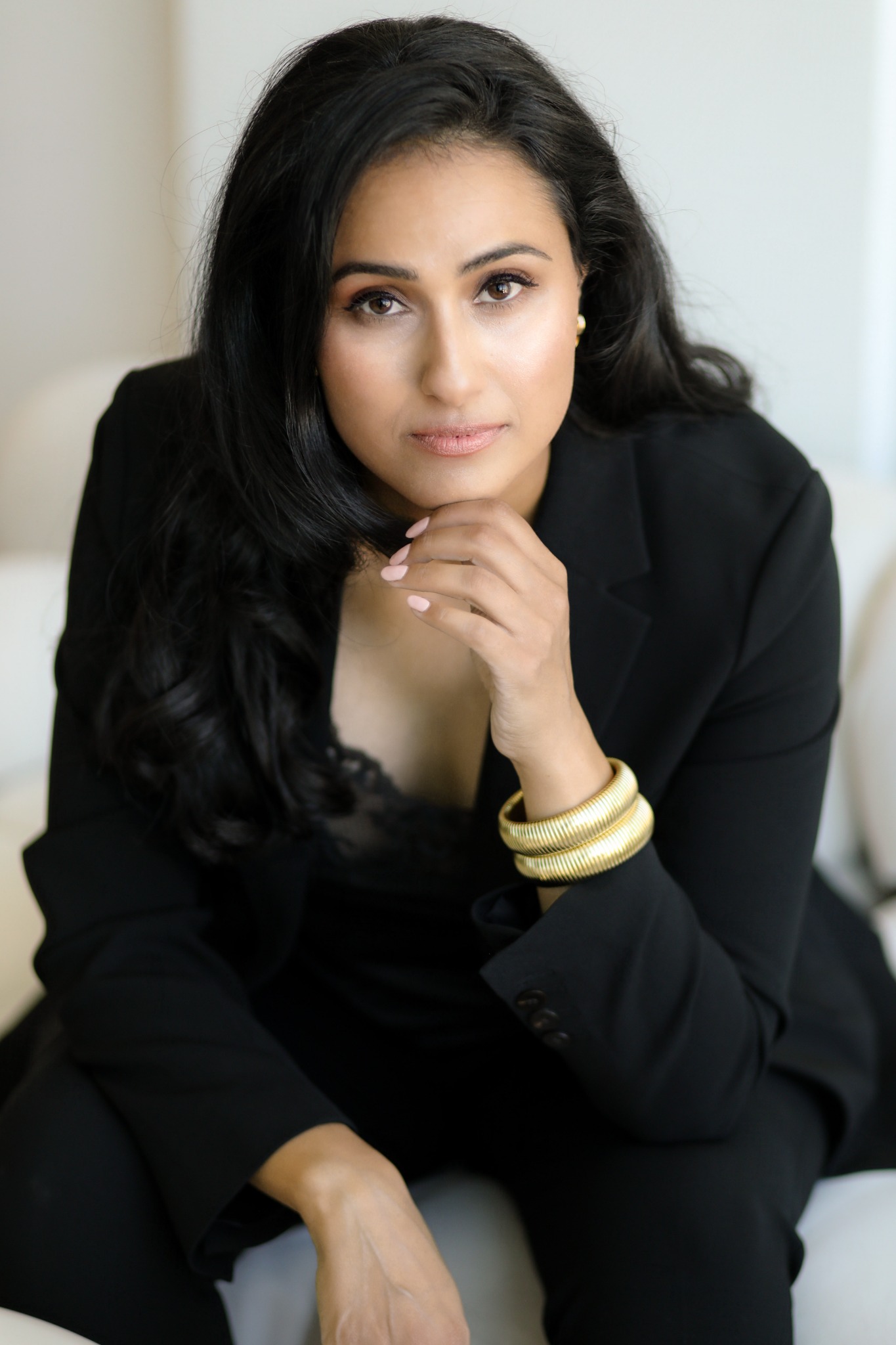 Heather Barahmand in a black suit, resting her chin on her hand